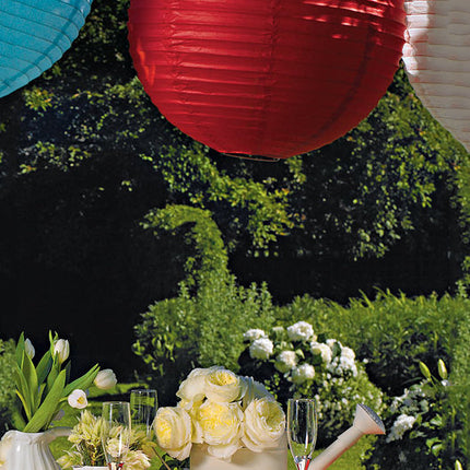Round Paper Lanterns hanging outdoors above a table. 