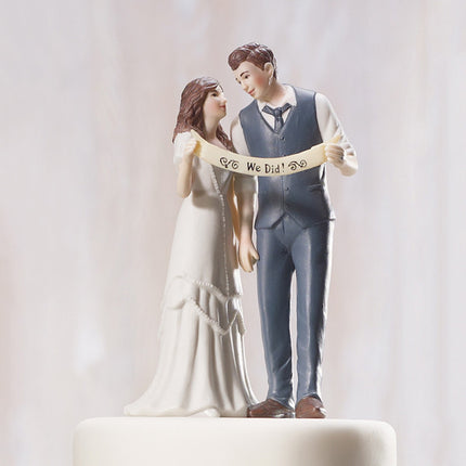 An Indie Wedding Couple Porcelain Cake Top sitting atop an off white wedding cake.